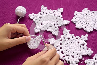 Woman knits crochet Christmas decoration â€“ snowflakes Stock Photo